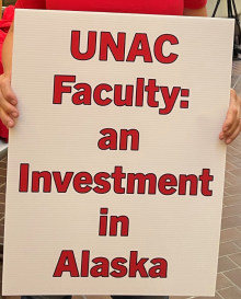 Picture of a person holding a large sign that says "UNAC Faculty: An Investment in Alaska"